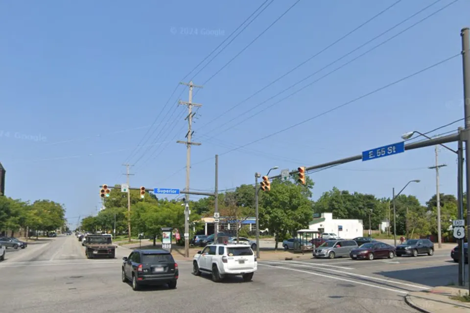 Google street view of wide street in Cleveland, Ohio with blue 55th Street sign and red brick three-story building visible in right corner.